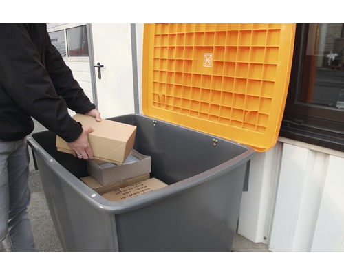 Person legt Pakete in eine graue Wertstofftonne mit offenem, orangefarbenem Deckel