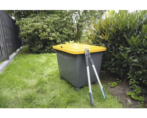 Gartenszene mit Komposter und Gartenschere auf Rasenfläche