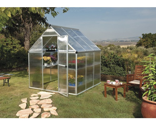 Gewächshaus mit Regalen und geöffneter Tür im Garten.