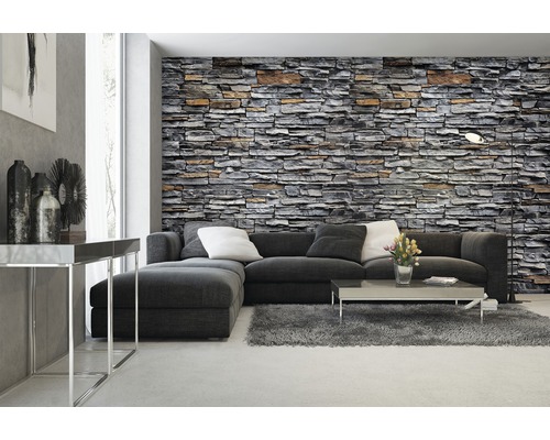 Wohnzimmer mit Steinwandtapete, Sofa, Teppich und Couchtisch.