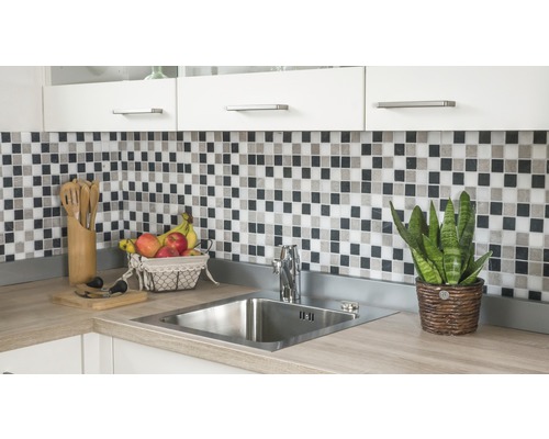 Küchenspüle mit Armatur, Mosaikfliesen und Küchenutensilien auf einer Küchentheke