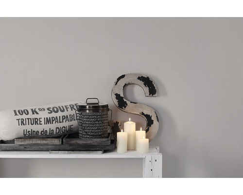 Dekorative Szene mit Kissen, Dose, Buchstaben und Kerzen auf einem Regal