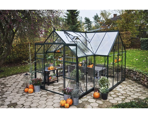 Gewächshaus im Garten mit Tisch, Stühlen und Herbstdekoration.