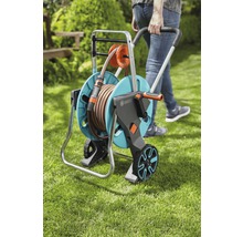 Person zieht einen Gartenschlauchwagen mit einem Schlauch darauf durch den Garten.