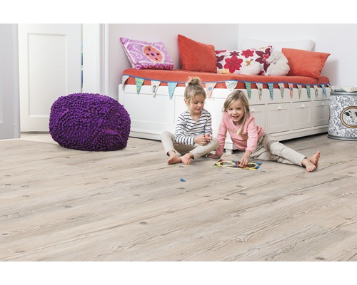 Kinderzimmer mit hellem Holzboden, Sitzbank, Kissen, Spielzeug und zwei spielenden Mädchen