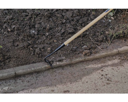 Gartenhacke mit Holzgriff im Einsatz neben einem Bordstein