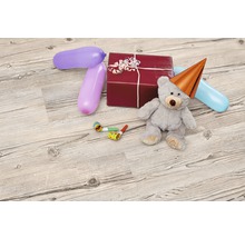 Dekoratives Arrangement mit Geschenk, Teddybär mit Partyhut, Ballons und Tröten auf Holzboden
