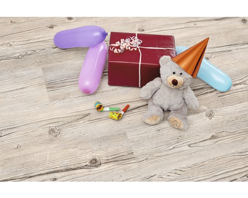 Dekoratives Arrangement mit Geschenk, Teddybär mit Partyhut, Ballons und Tröten auf Holzboden