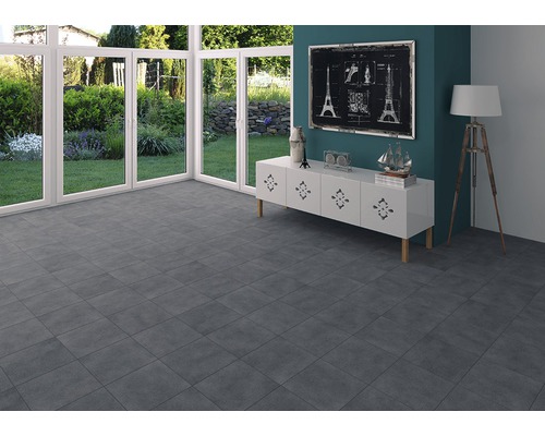 Heller Raum mit grauen Fliesen, weißen Fenstern und Kommode