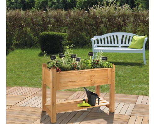 Hochbeet aus Holz mit Pflanzenetiketten, Gießkanne und Gartengeräten im Garten