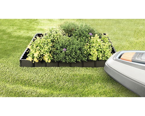 Beetbegrenzung aus Kunststoff mit Pflanzen und Rasenmähroboter im Garten.