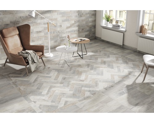 Heller Wohnraum mit Fliesenboden in Fischgrätmuster, Sessel und Stehlampe