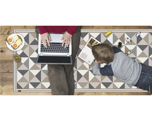 Spielteppich mit geometrischem Dreiecksmuster, darauf Kind, Laptop und Speisen