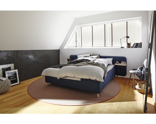 Schlafzimmer mit Bett, Teppich und dekorativen Elementen in einem hellen Dachgeschoss