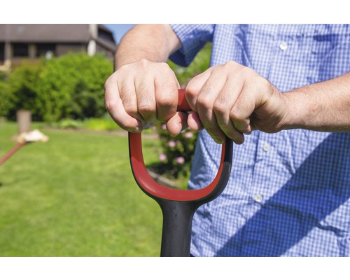 Person hält einen Spaten mit D-Griff in einem Garten