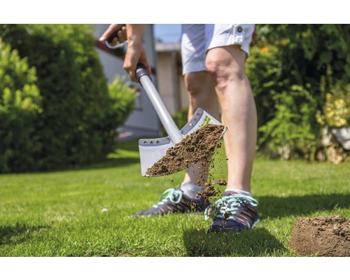 Eine Person benutzt einen Spaten, um Erde in einem Garten umzugraben.