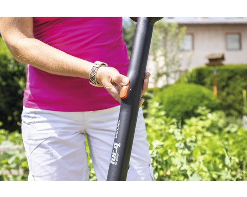 Eine Person bedient ein Gartengerät mit Teleskopstiel im Garten.
