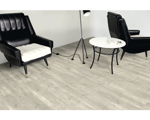 Wohnraum mit hellem Laminatboden, Sesseln, Tisch und Stehlampe
