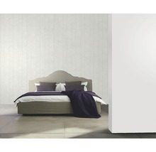Schlafzimmer mit Bett, Kissen und Tagesdecke vor einer Wand mit Holzpaneelen