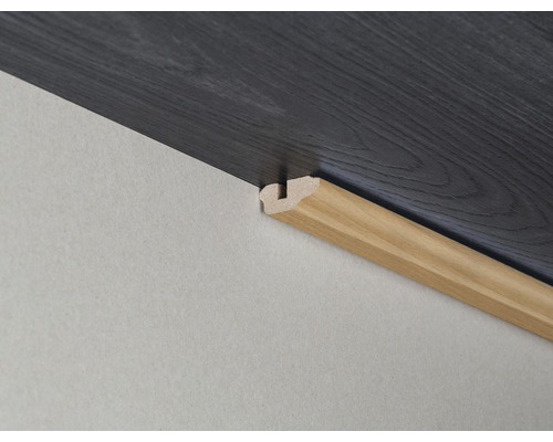 Detailaufnahme einer Holzfußleiste an einer Wand mit Laminatboden