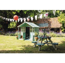 Szene im Garten mit Spielhaus und Picknicktisch unter Girlanden.