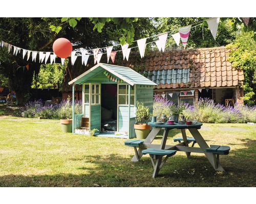 Szene im Garten mit Spielhaus und Picknicktisch unter Girlanden.