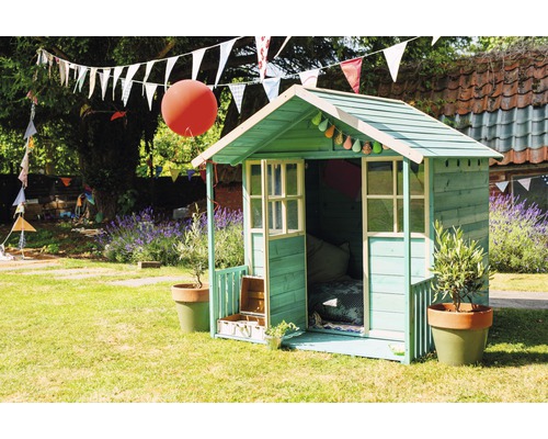 Ein grünes Kinderspielhaus im Garten mit Dekoration und Pflanzen.