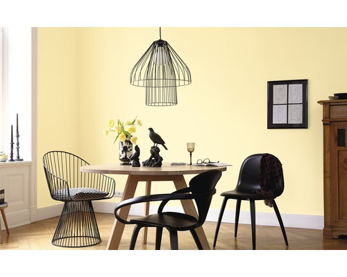 Esszimmer mit rundem Tisch, Stühlen und Pendelleuchte vor gelber Wand