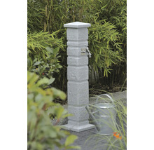 Gartenzapfstelle aus Stein mit Wasserhahn und Gießkanne im Garten