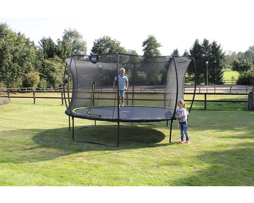 Trampolin mit Sicherheitsnetz im Garten, darauf ein springendes Kind