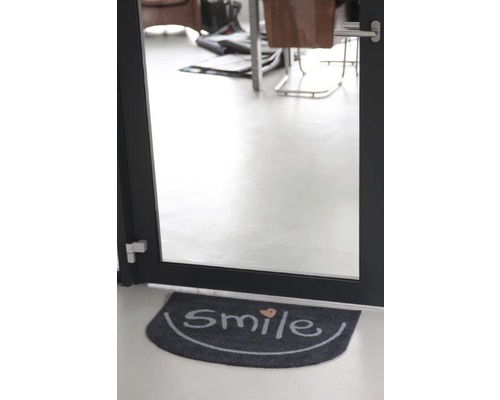 Fußmatte mit der Aufschrift Smile vor einer Tür
