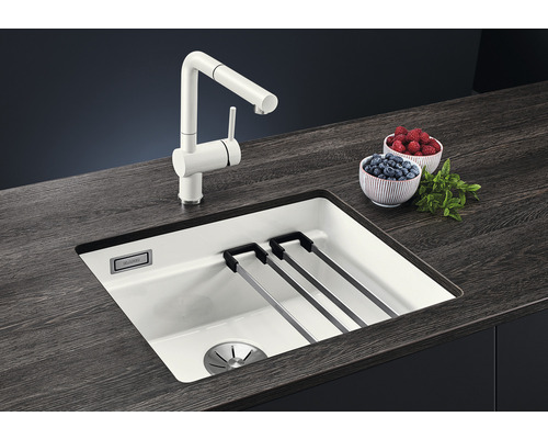 Küchenspüle mit Abtropfgitter und Armatur auf einer dunklen Arbeitsplatte mit Schalen mit Beeren