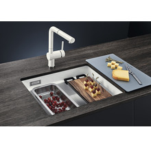 Küchenspüle mit Armatur, Schneidebrett und Lebensmitteln auf einer Arbeitsplatte