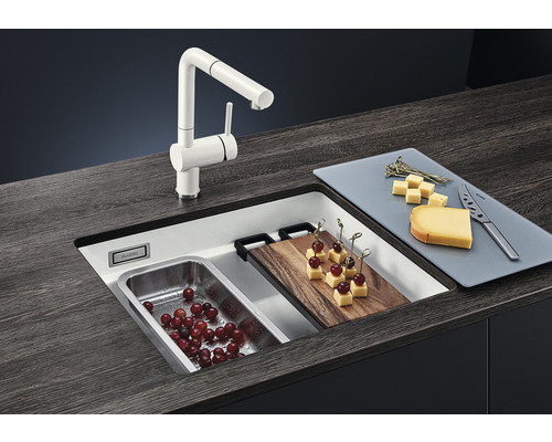 Spüle mit Armatur, Schneidebrett, Edelstahlbehälter und Lebensmitteln auf einer Arbeitsplatte