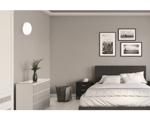 Schlafzimmer mit Bett, Kommode, Nachttisch, Wandleuchte und Dekoration