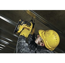 Ein Handwerker befestigt mit einem Akku-Bohrhammer eine Metallschiene an einer Betondecke.