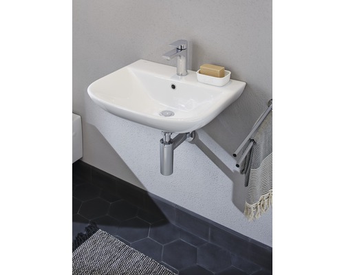 Keramikwaschtisch mit Armatur und Handtuchhalter im Badezimmer