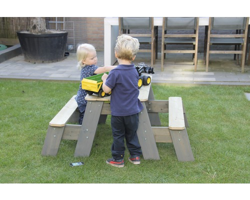 Kinder spielen an einem grauen Kindersitzgarnitur im Garten.