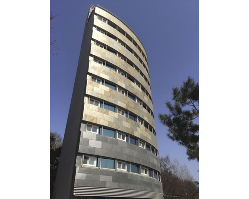 Ein hohes Gebäude mit mehreren Fenstern und einer Fassade aus Naturstein.