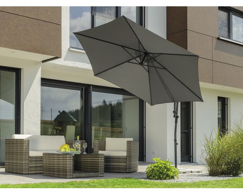 Szene mit einer Rattansitzgruppe unter einem rechteckigen Sonnenschirm im Garten