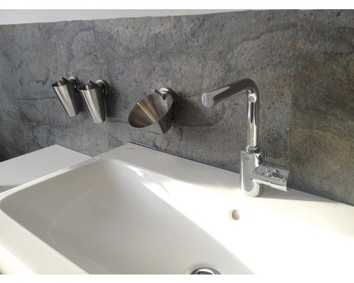 Waschbecken mit Armatur und Seifenspender vor einer grauen Wand