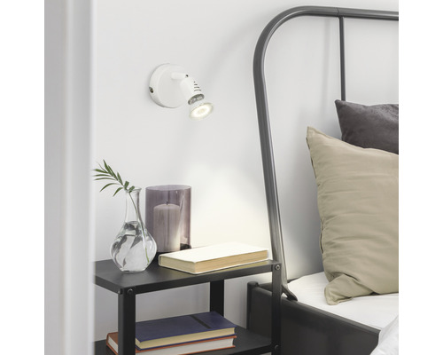 Schlafzimmer mit Wandleuchte, Nachttisch und Bett