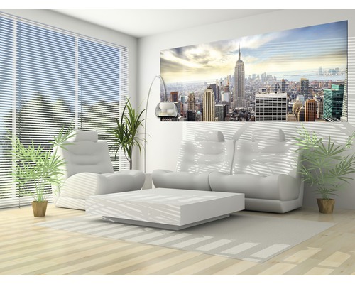 Heller Wohnraum mit Sofa, Sessel, Tisch, Zimmerpflanzen und Wandbild mit Stadtansicht