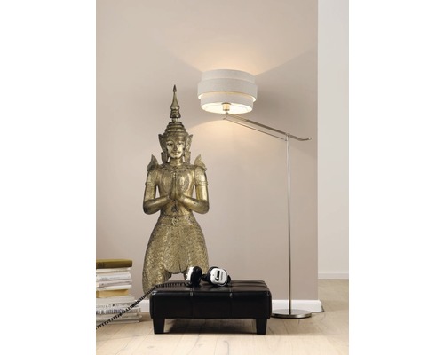 Dekorative Bodenszene mit einer Buddha-Statue, einem Hocker, einem Bücherstapel, einem Kopfhörer und einer Stehlampe