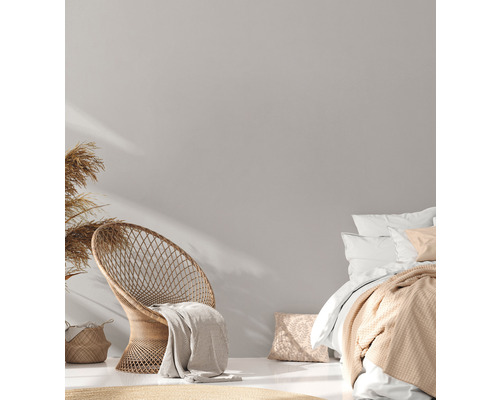 Helles Schlafzimmer mit Korbstuhl und Bettwäsche