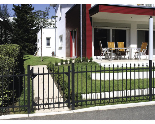 Gartenszene mit einem schwarzen Metallzaun und Tor vor einem Wohnhaus.