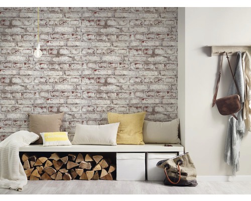Wohnraum mit Tapete in Ziegeloptik, Sitzbank mit Kissen und Holzlagerfach.