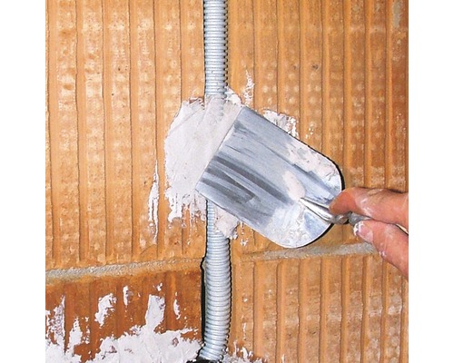 Ein Elektriker verputzt eine Wand mit einer Kelle.