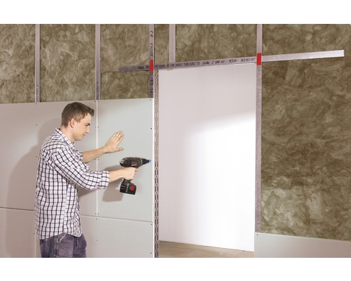 Mann befestigt eine Gipskartonplatte mit einem Akkubohrer an einem Ständerwerk.