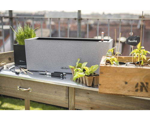 Szene mit Pflanztisch, Pflanzgefäßen und Gartenzubehör für den Außenbereich.